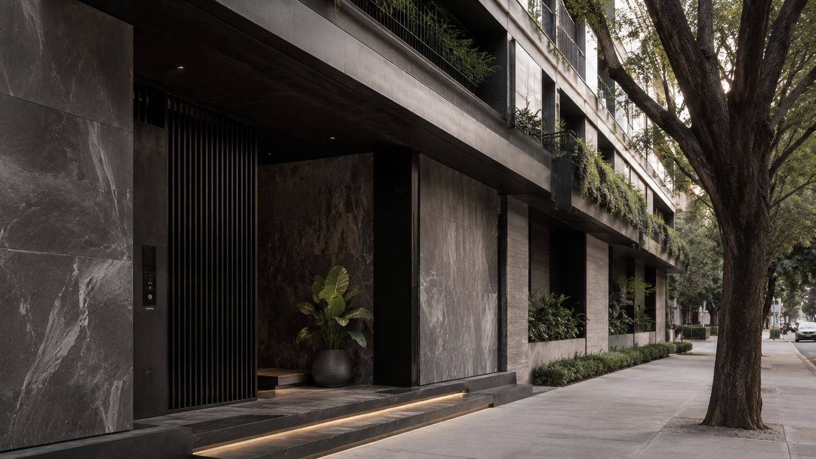 Entrance to a contemporary stone-clad apartment building on a tree-lined Mexico City street